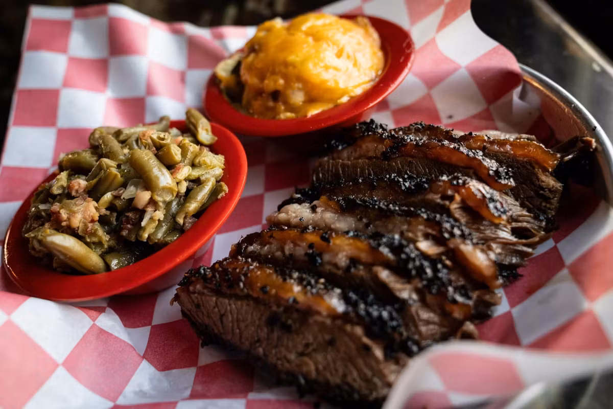Sliced smoked brisket with mac and cheese and sweet potatoes