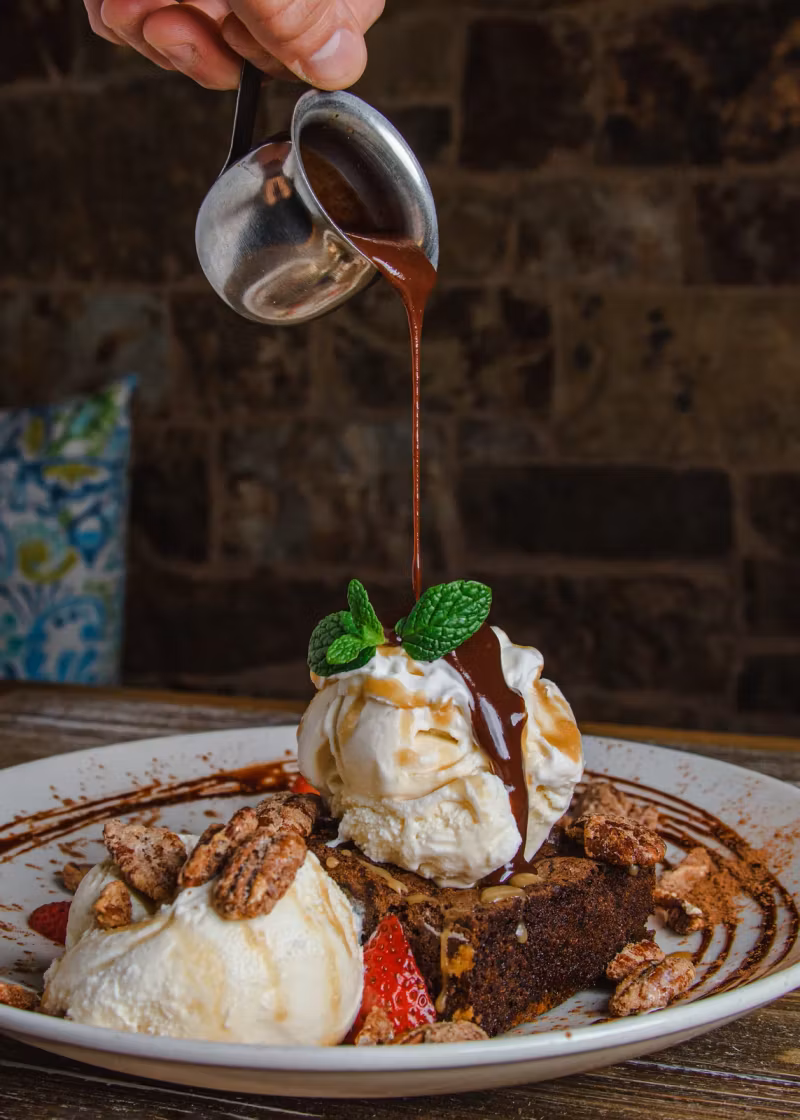 Chocolate sauce poured over a brownie sundae