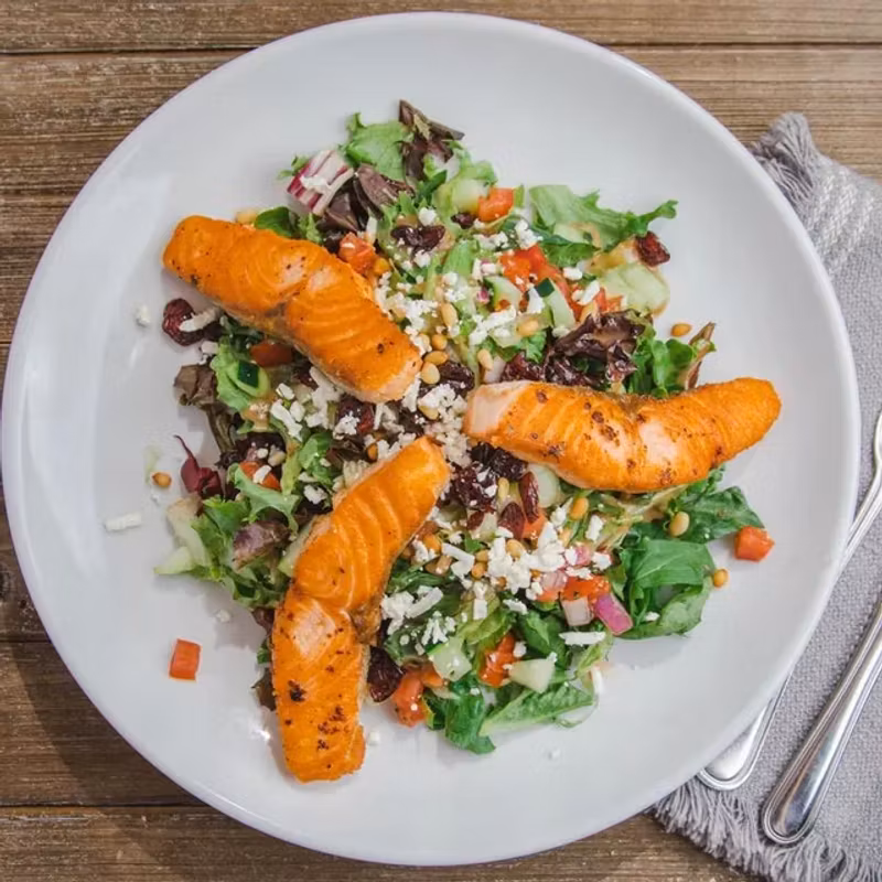 Salmon salad with mixed greens, feta, pine nuts, and balsamic basil dressing