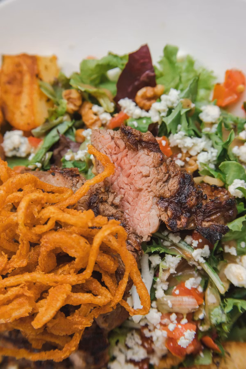 Steak salad with sliced steak, crispy onions and mixed greens